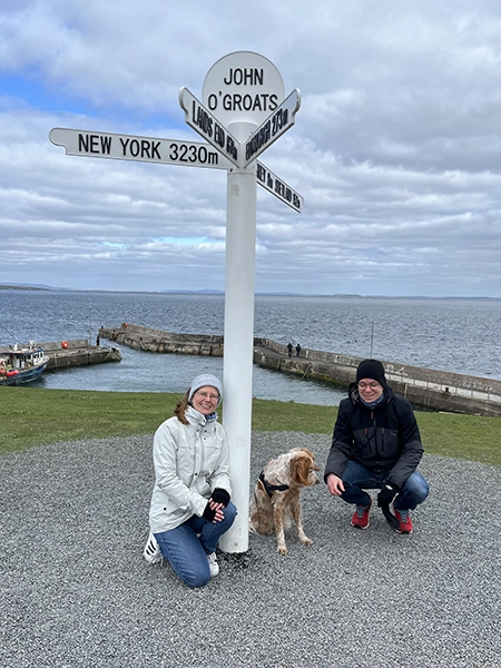 couple avec chien qui pose devant le panneau à John O' Groats en Ecosse